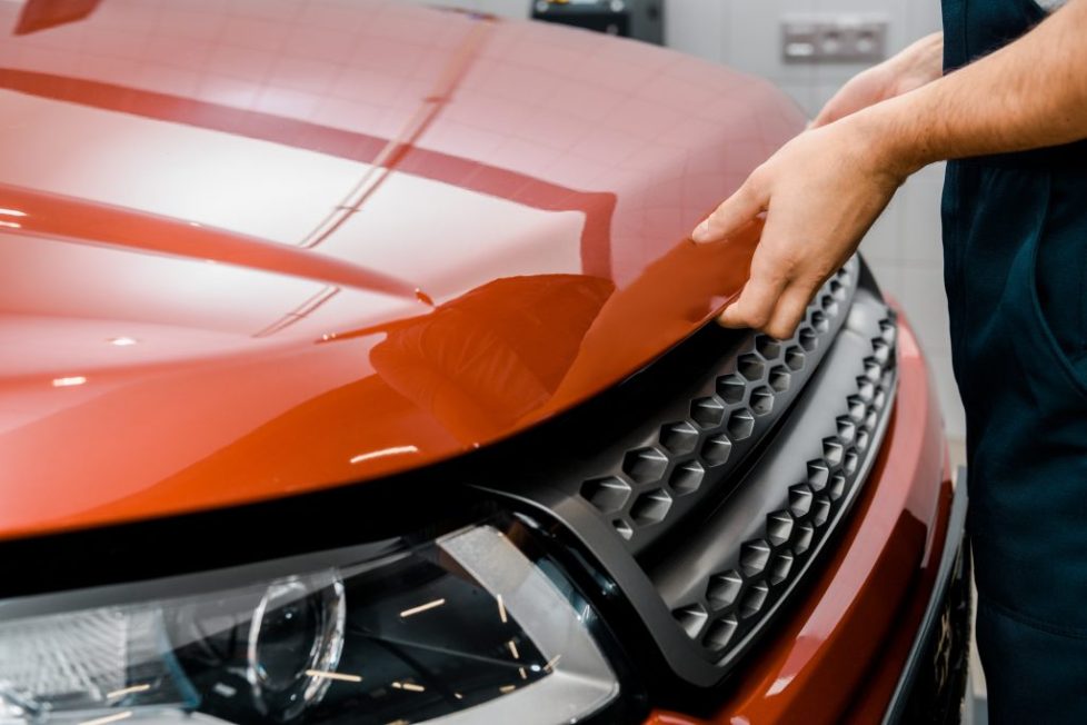 New Vehicle servicing at R & L Automotive mechanics with a close up of mechanic opening an new orange car bonnet