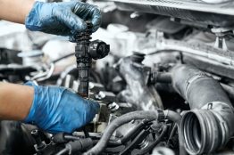 Mechanics hands in rubber gloves replacing ignition coil on car